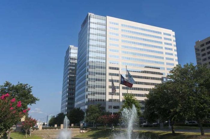 TechnipFMC office tower behind fountains, with the Texas flag flying at the entrance plaza