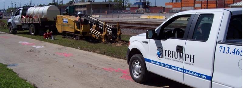 Triumph service truck and vacuum excavation trailer parked at a marked jobsite